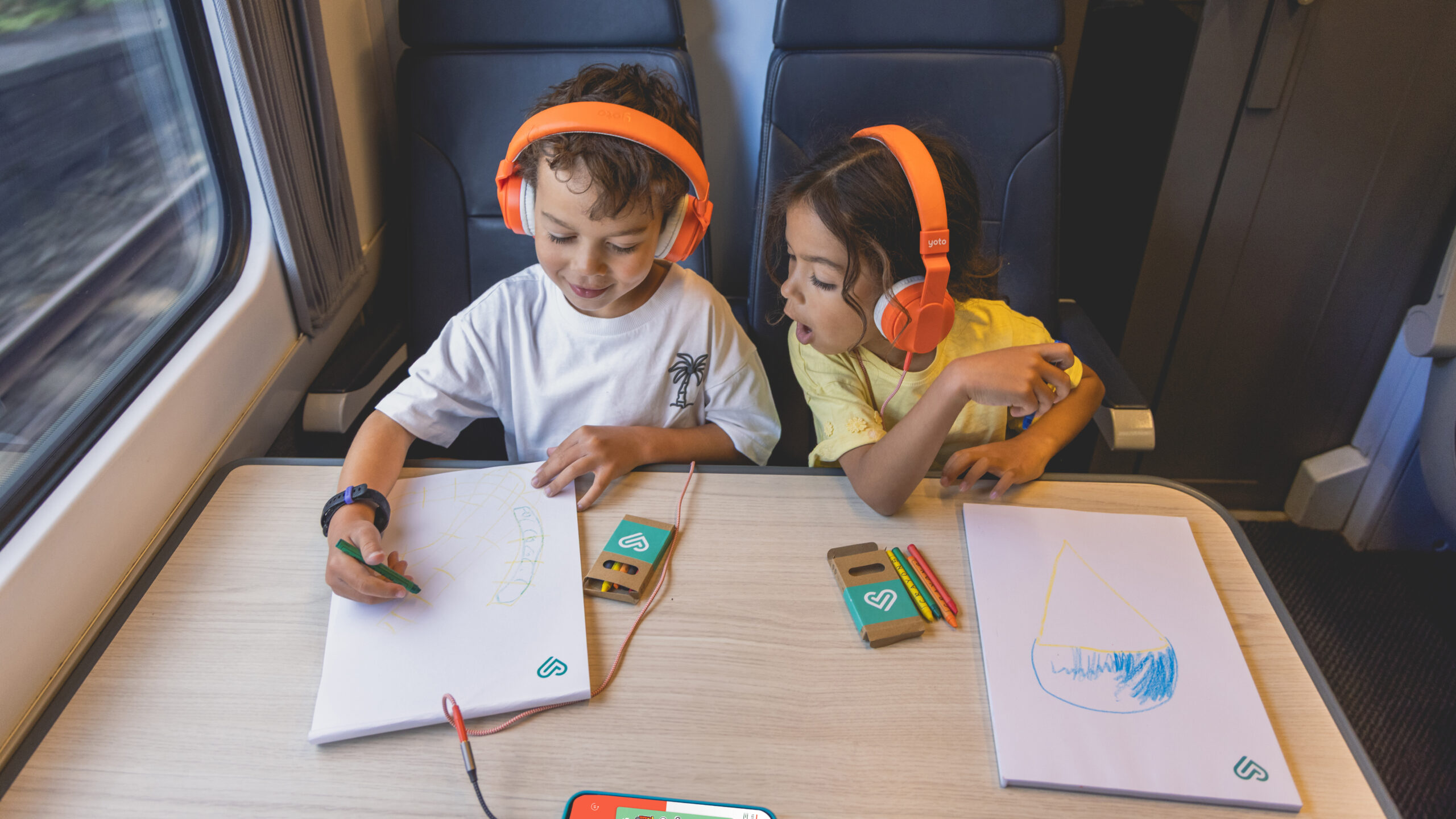 Deux enfants profitent des audios Trainline x Yoto.